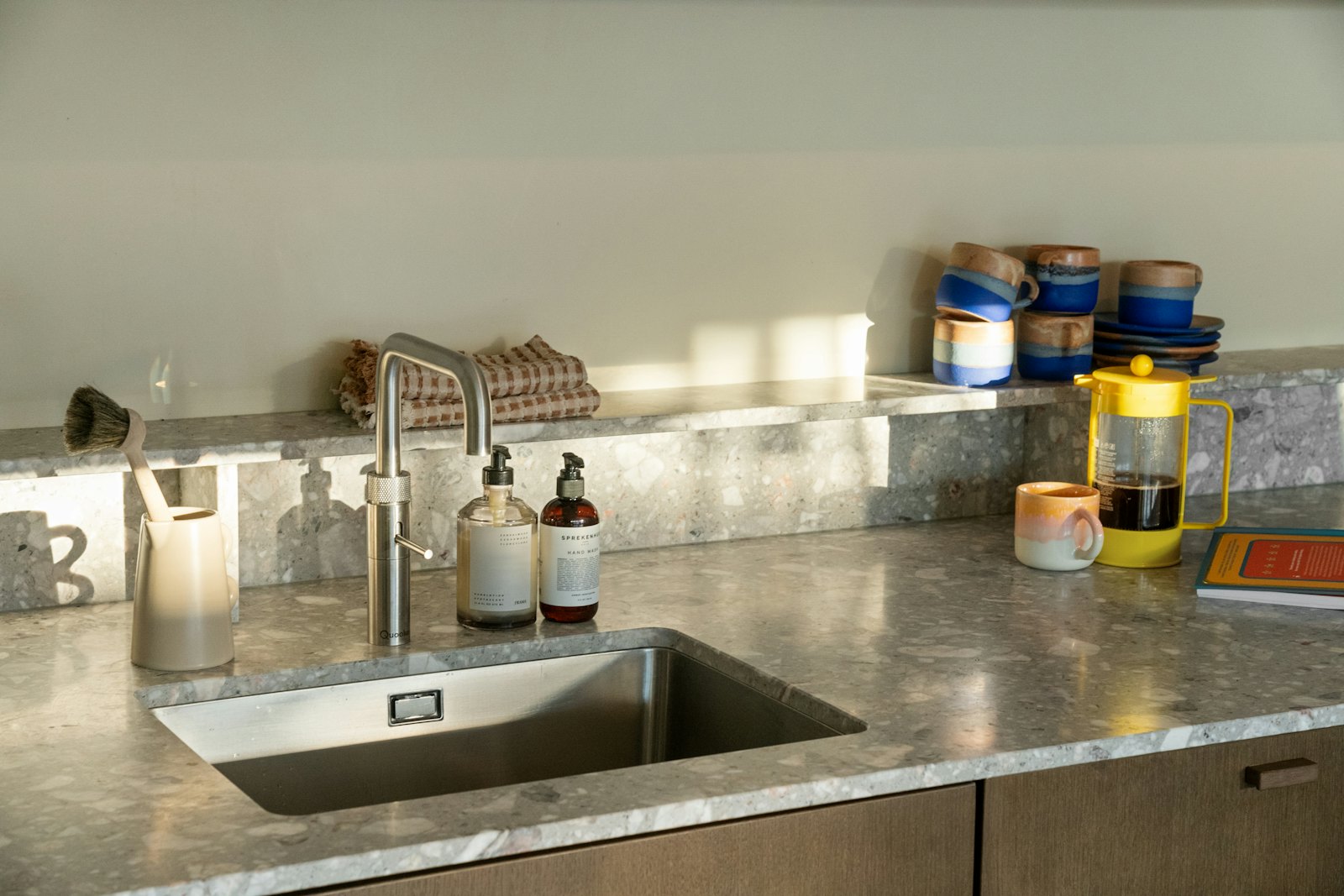 Speckled stone-look kitchen countertop with an undermount steel sink, faucet and backsplash shelf