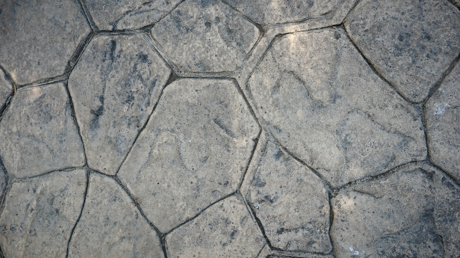 Close-up of a grey random-flagstone pattern pavement with crisp joints (stamped-concrete look)