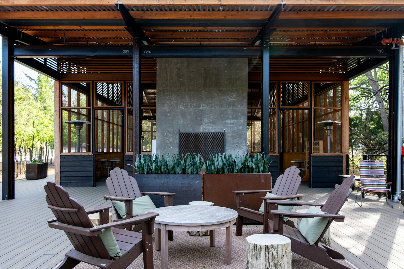 Covered pavilion with a tall outdoor fireplace and Adirondack chairs around a low round table