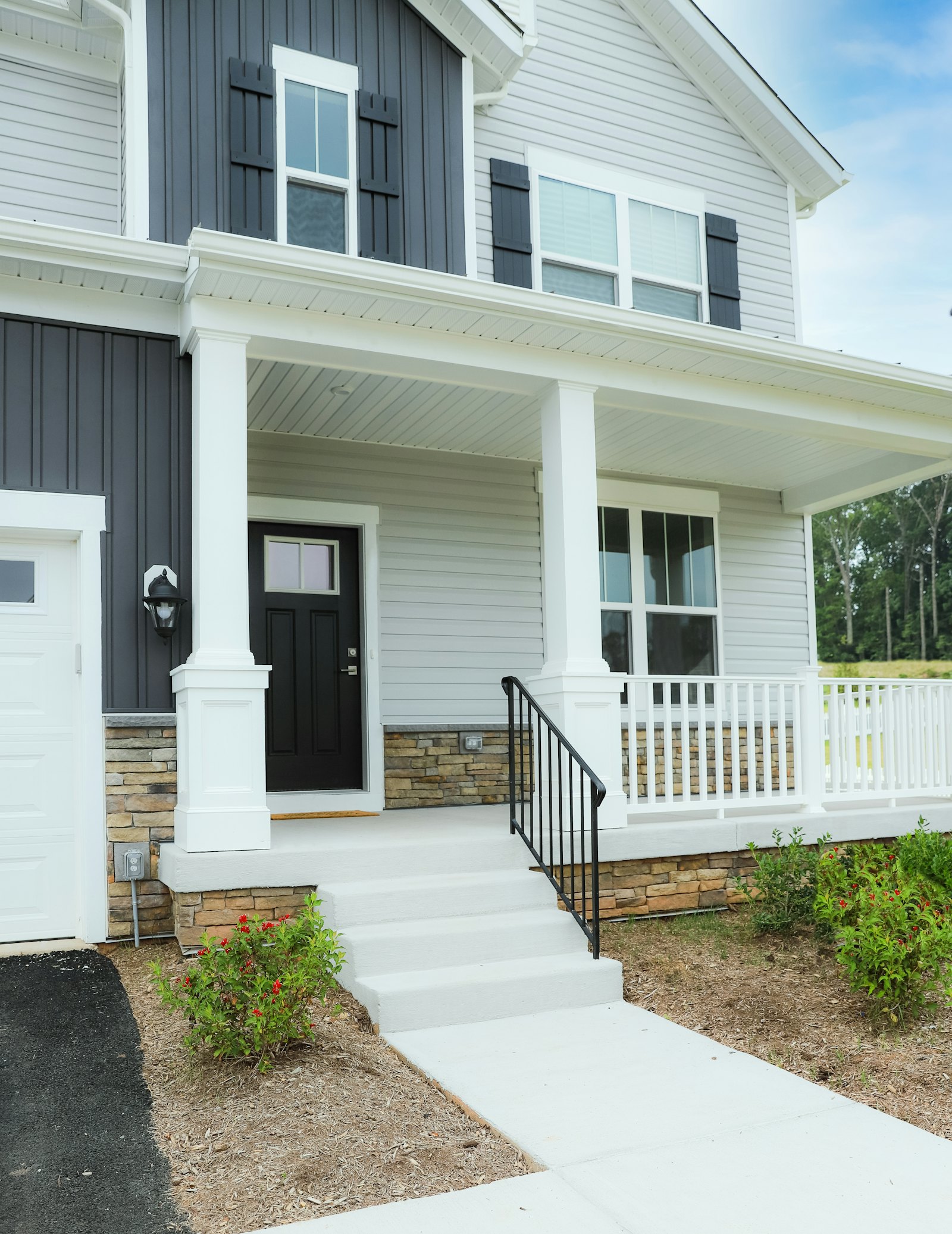 New concrete front walk and steps leading to a covered porch with white railings
