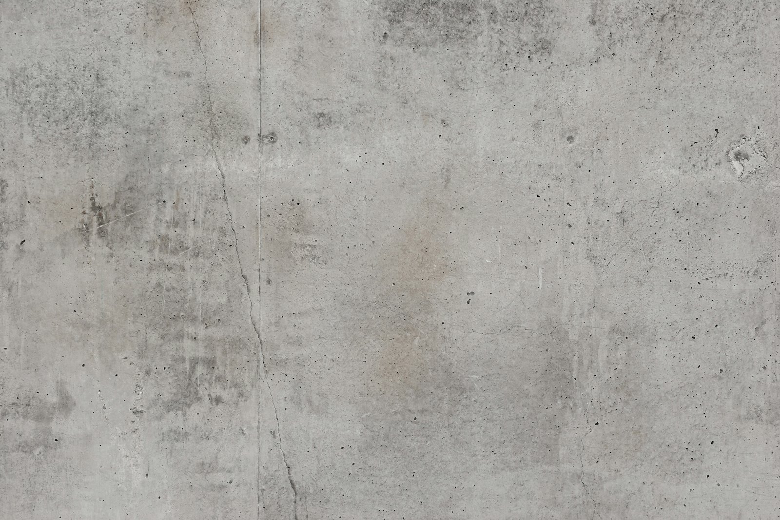 Grey concrete wall with faint hairline cracks and mottling